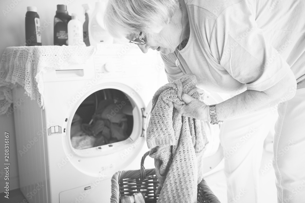 Elderly woman doing laundry at home