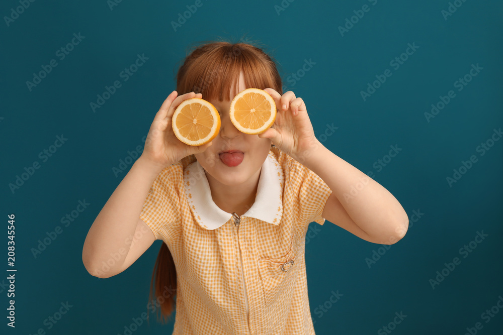 Funny little girl with citrus fruit on color background