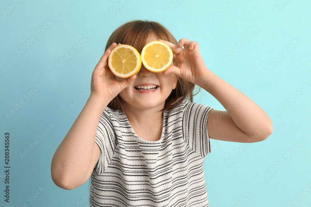 Funny little girl with citrus fruit on color background