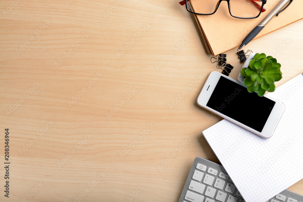 Workplace composition with smartphone, computer keyboard and stationery on table