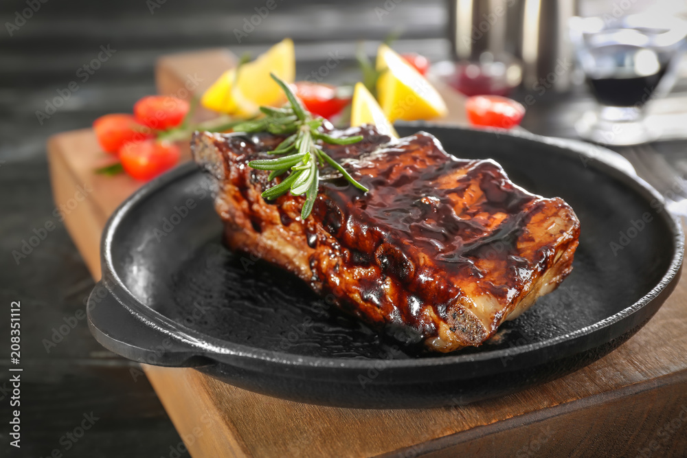 Frying pan with delicious grilled ribs   on wooden board