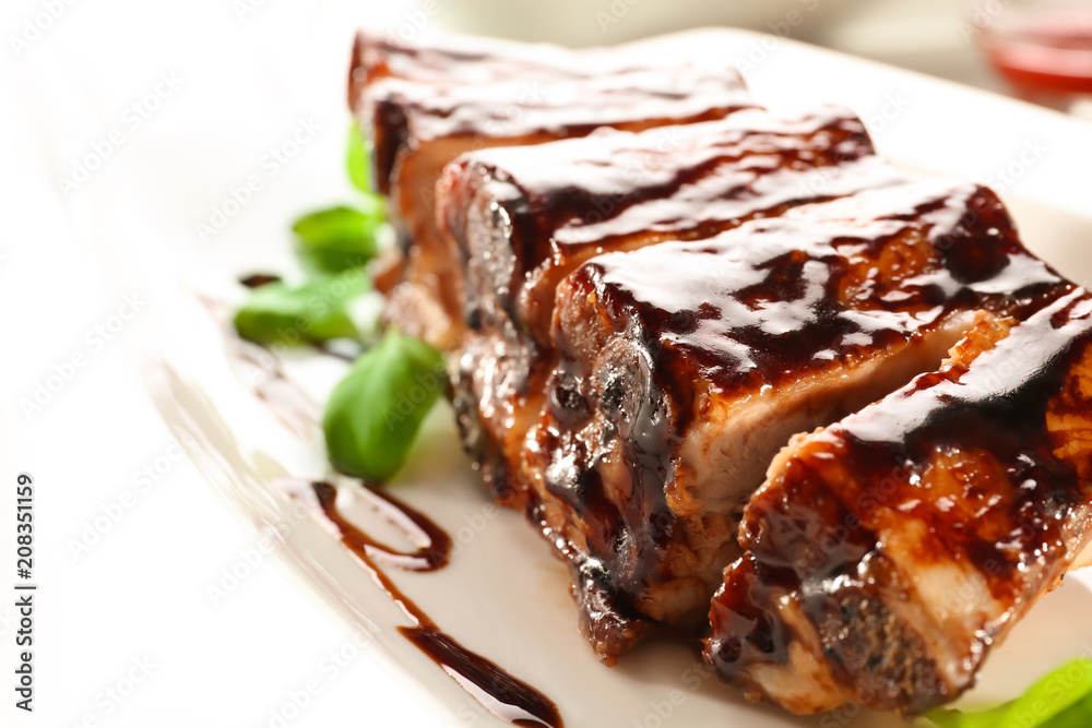 Delicious grilled ribs with sauce on plate, closeup