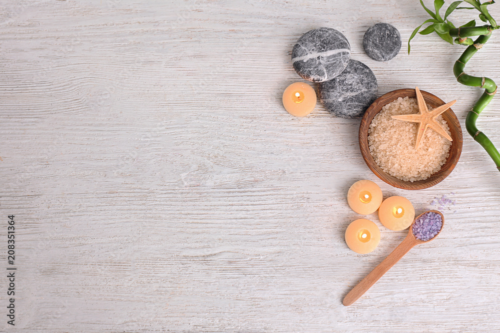 Candles with sea salt and stones for spa treatment on wooden background