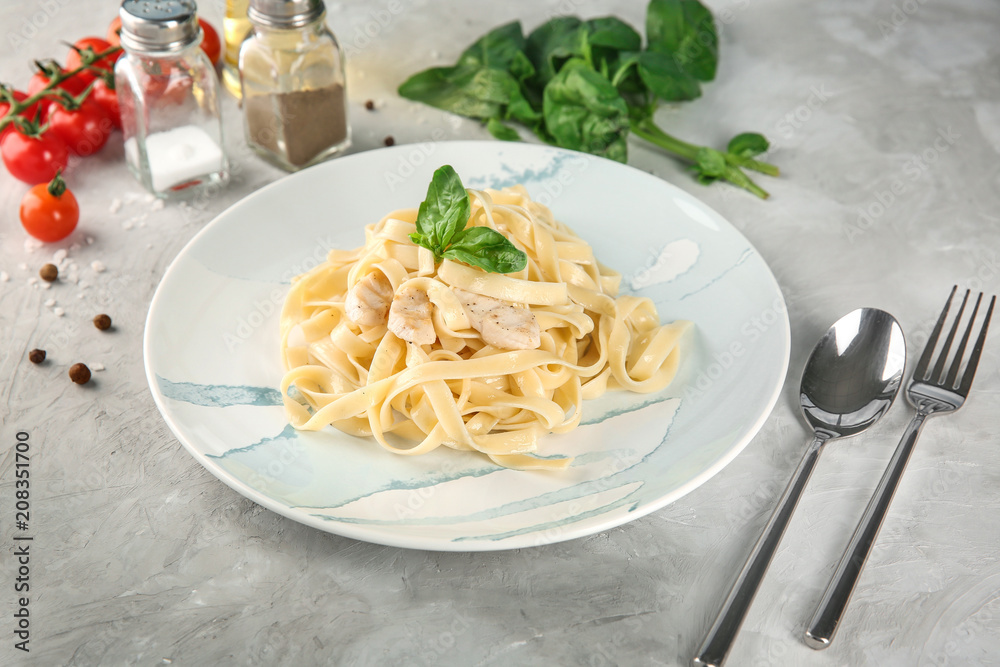 Plate of tasty pasta with chicken fillet on table