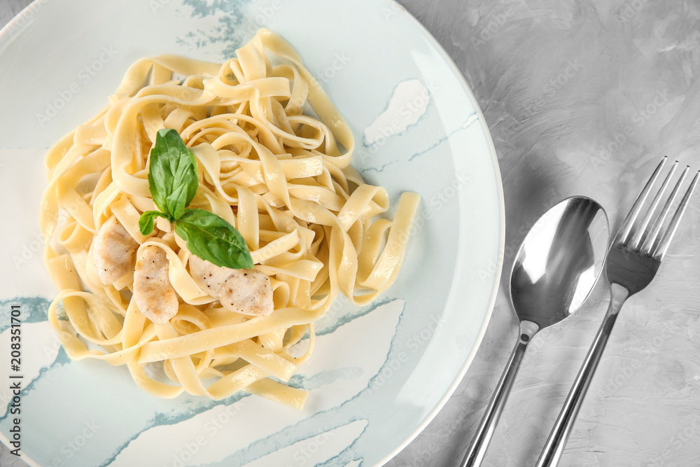 Plate of tasty pasta with chicken fillet on table, top view