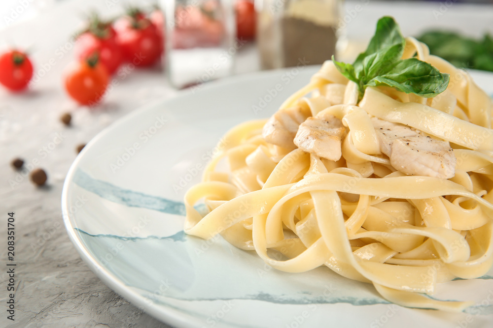 Plate of tasty pasta with chicken fillet on table, closeup