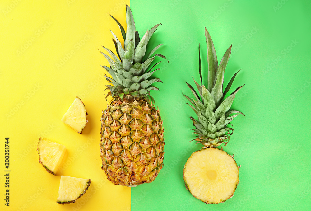 Whole and sliced fresh pineapples on color background