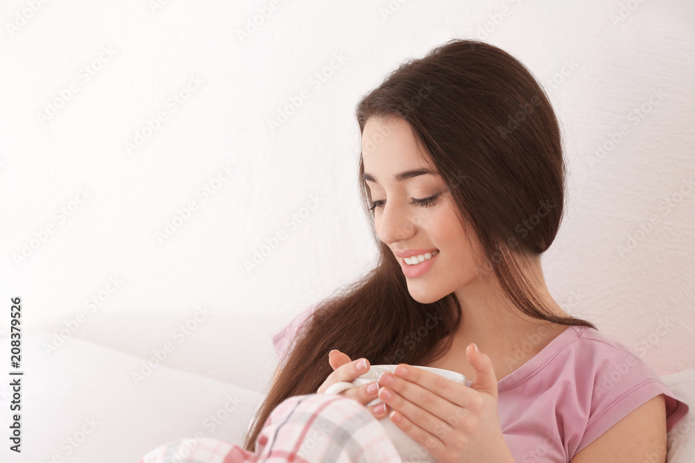 Beautiful young woman with cup of hot tea at home