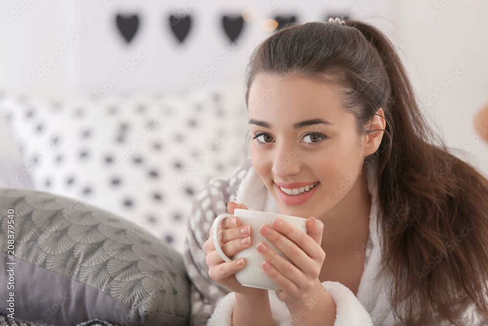 家里有一杯热茶的漂亮年轻女人