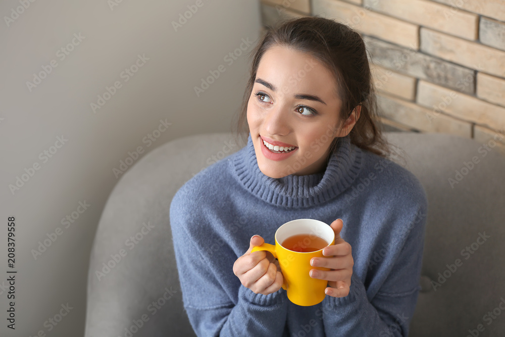 Beautiful young woman with cup of hot tea at home