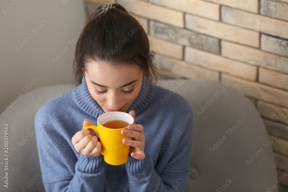 家里有一杯热茶的漂亮年轻女人