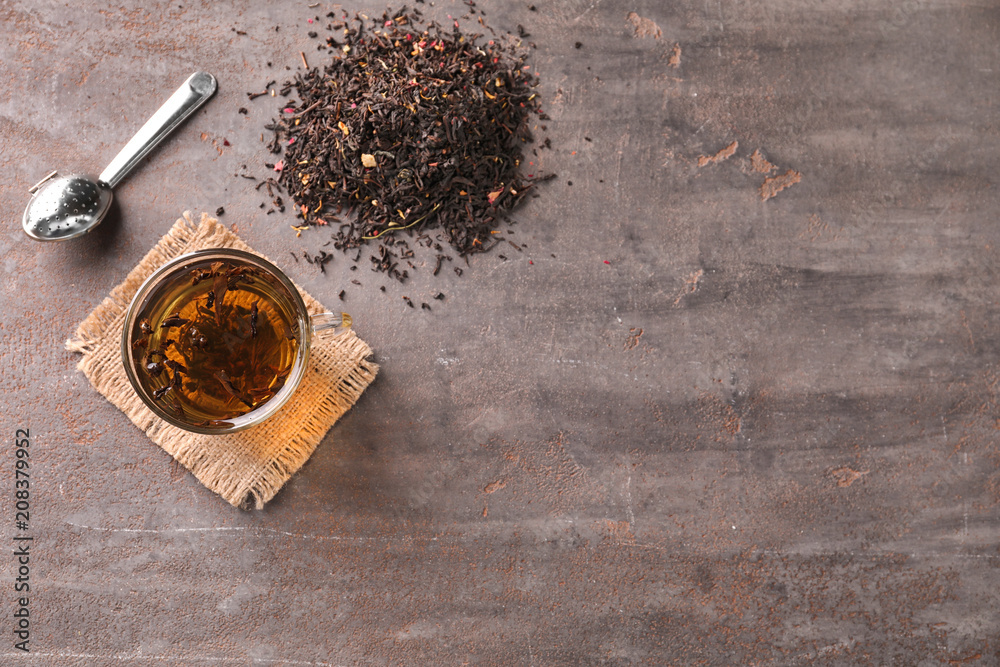 Flat lay composition with dry tea leaves and hot beverage on grey background