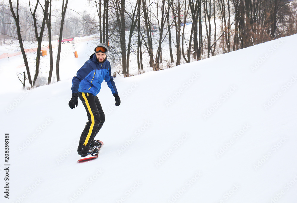 冬季度假区斜坡上的男单板滑雪运动员