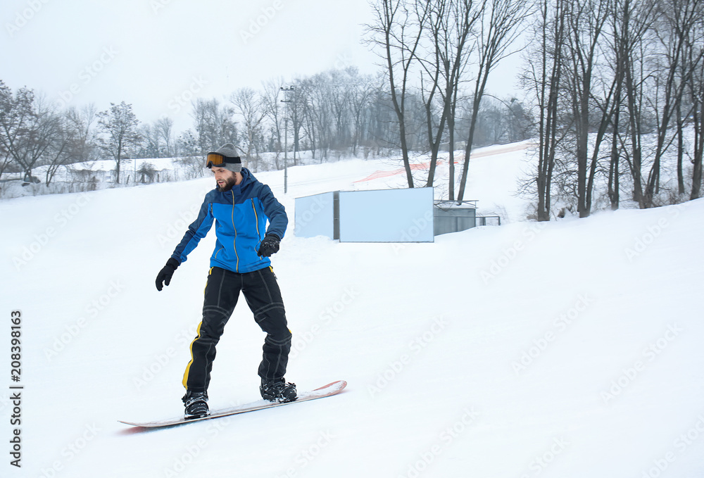 冬季度假区斜坡上的男单板滑雪运动员