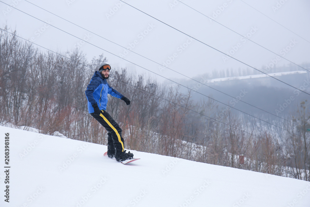 冬季度假区斜坡上的男单板滑雪运动员