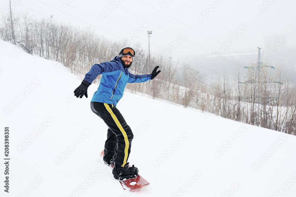 冬季度假胜地斜坡上的男单板滑雪运动员