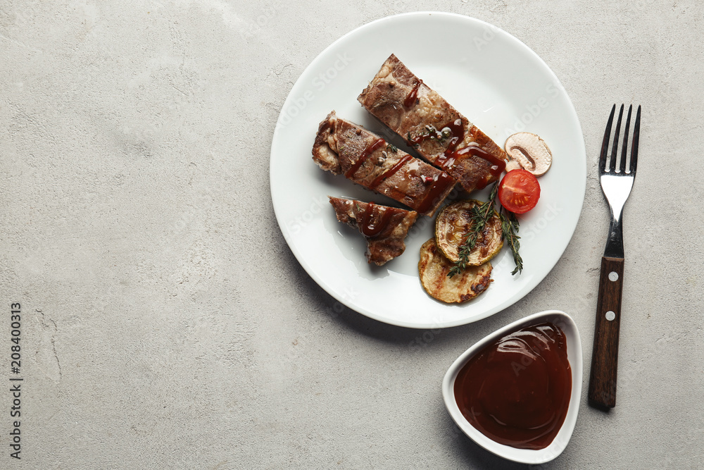 Plate of grilled meat with vegetables and barbecue sauce on table, top view