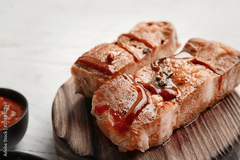 Delicious grilled meat with barbecue sauce on wooden board, closeup