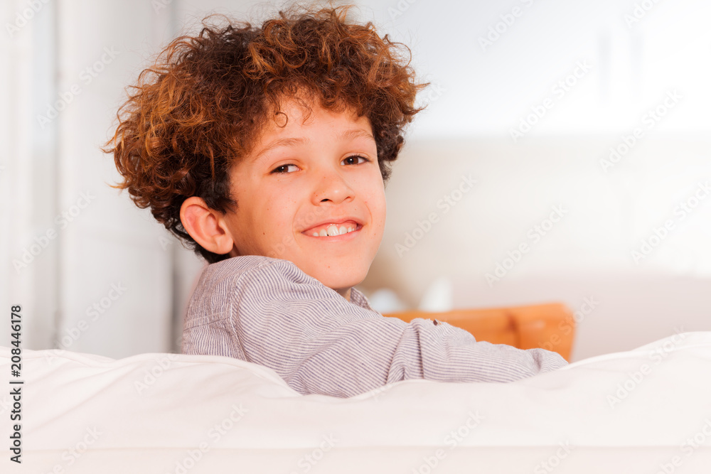 Boy sitting backwards on white sofa in lounge room