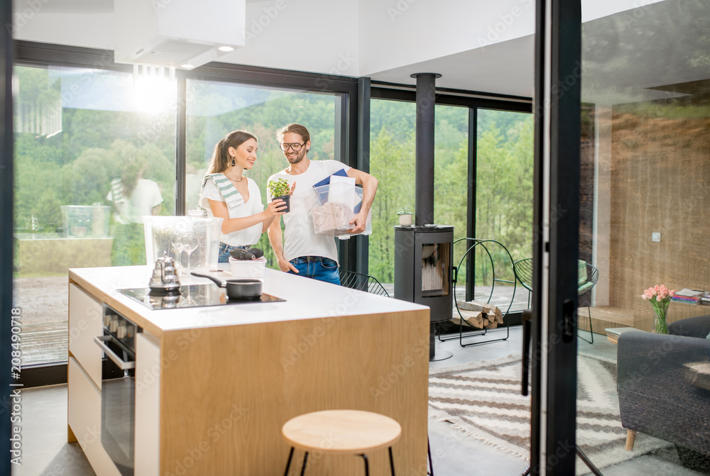 Young and happy couple unpacking different home stuff making order in their new and modern house