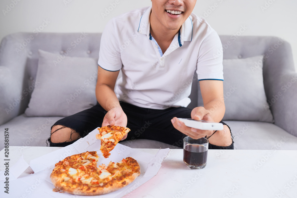 Man eating pizza having a takeaway at home relaxing resting