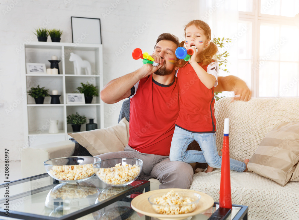 family of fans watching a football match on TV at home