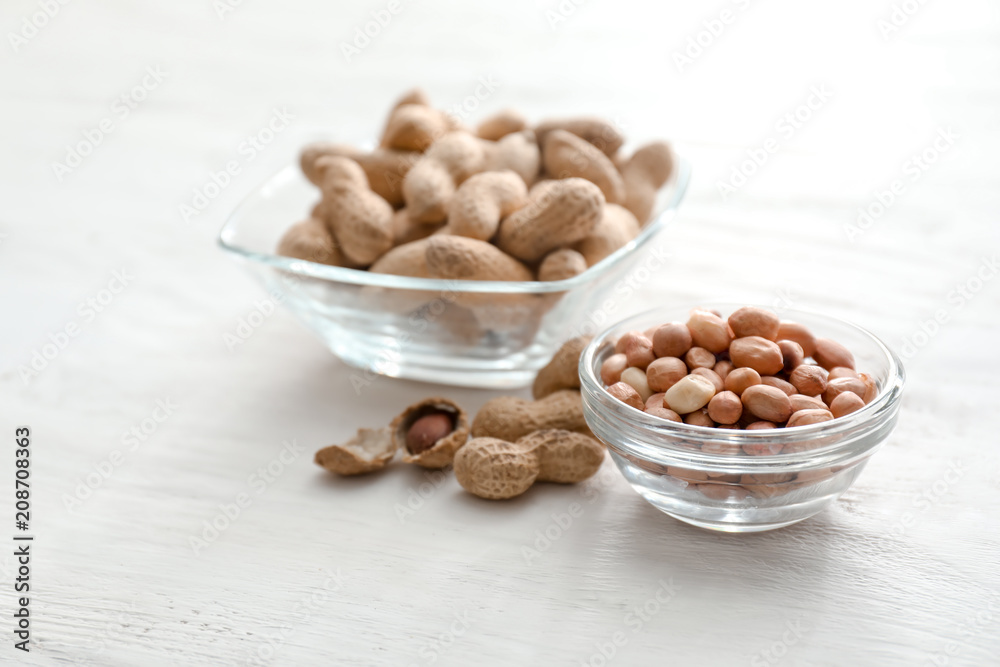 Bowls with tasty peanuts on wooden table