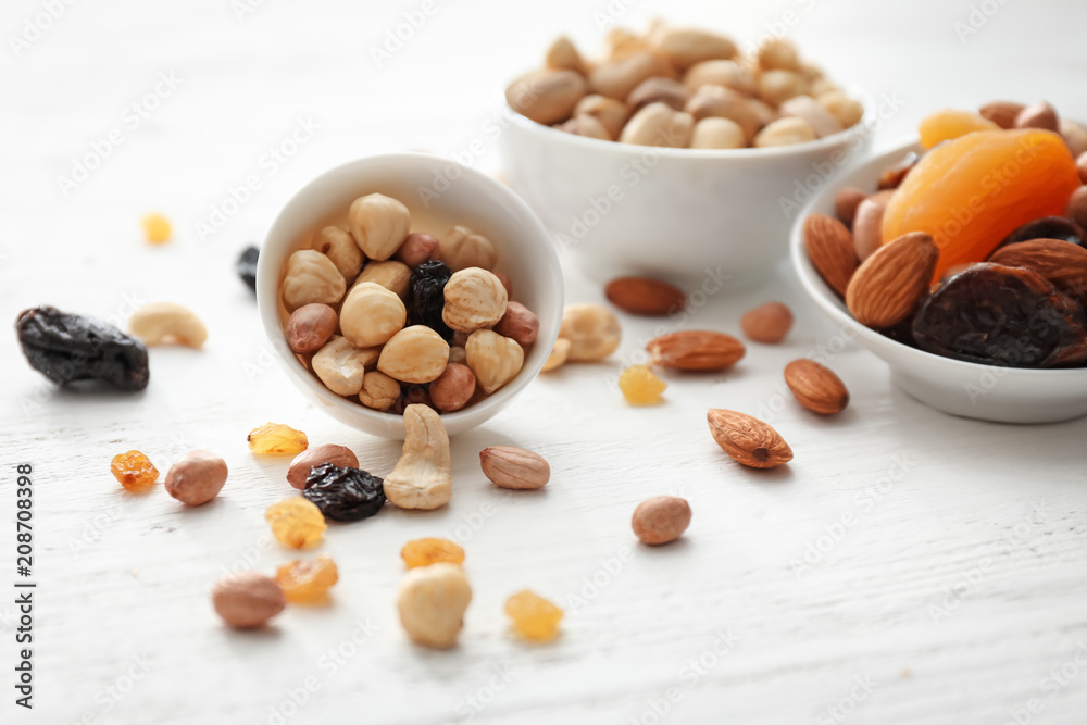 Bowls with various tasty nuts and dried fruits on wooden table