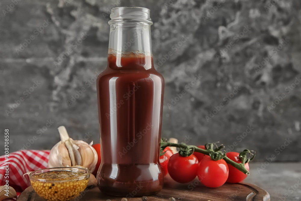 Bottle with tasty tomato sauce and vegetables on wooden board