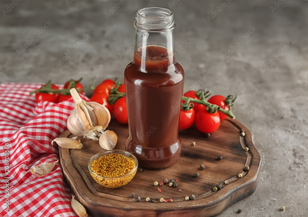 Bottle with tasty tomato sauce and vegetables on wooden board