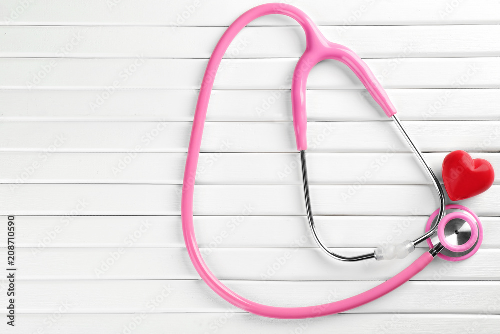 Stethoscope with small heart on white wooden background