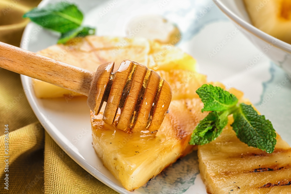 Grilled pineapple slices with honey on plate, closeup