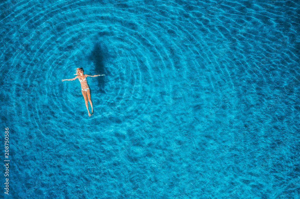 马尔代夫日落时游泳女子的鸟瞰图。地中海。年轻g的空中海景