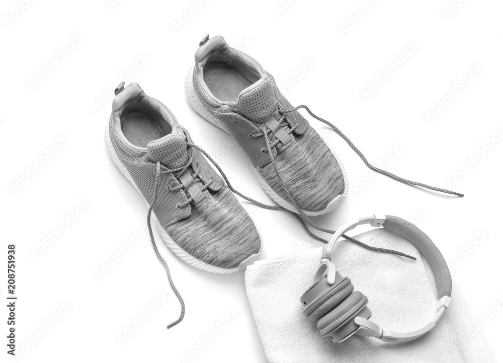 Sneakers, clean towel and headphones on white background