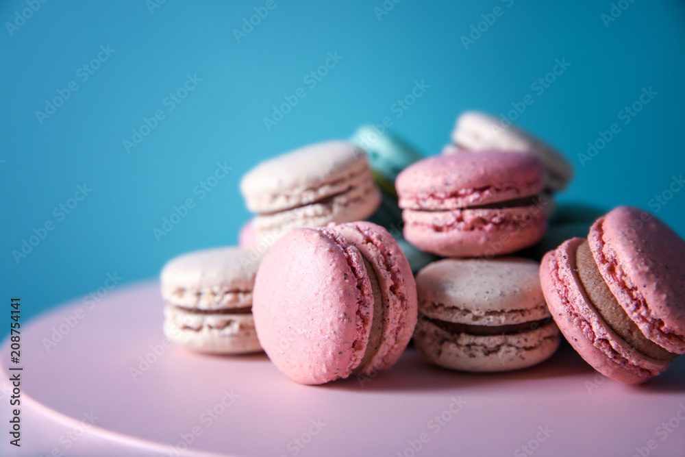 Dessert stand with tasty macarons on color background