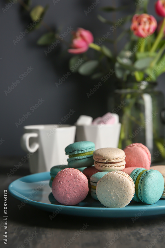 Plate with tasty macarons on table