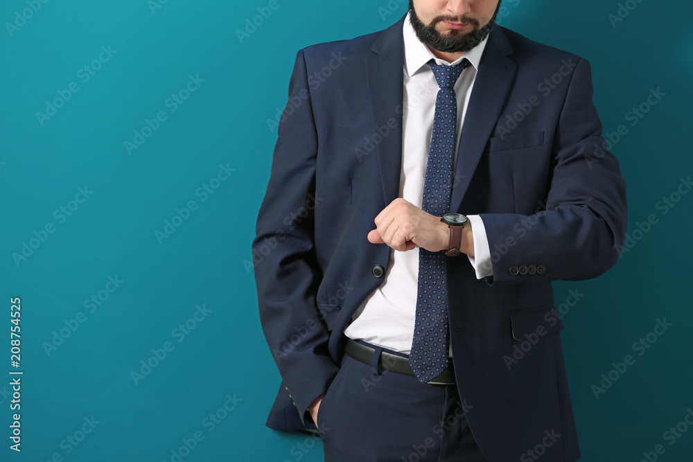 Man looking at his watch on color background. Time management concept