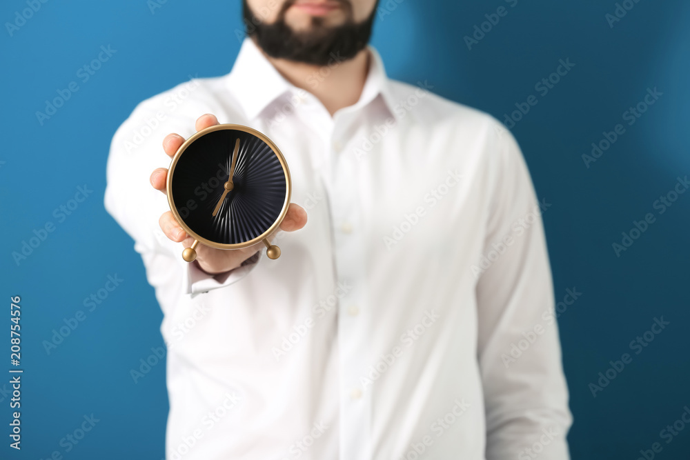 Man holding clock on color background. Time management concept