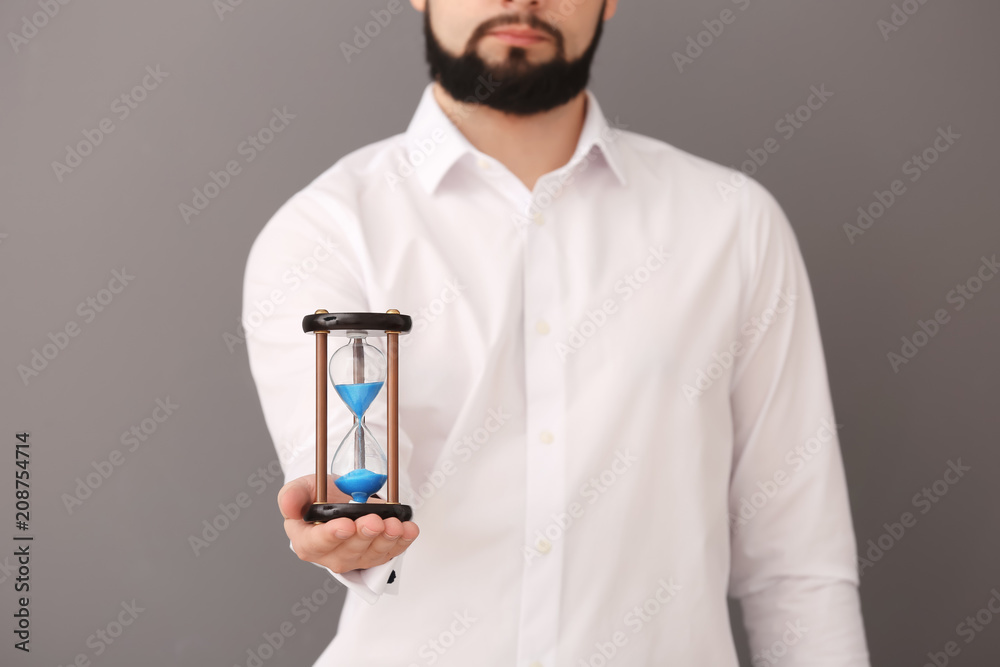 Man holding hourglass on gray background. Time management concept