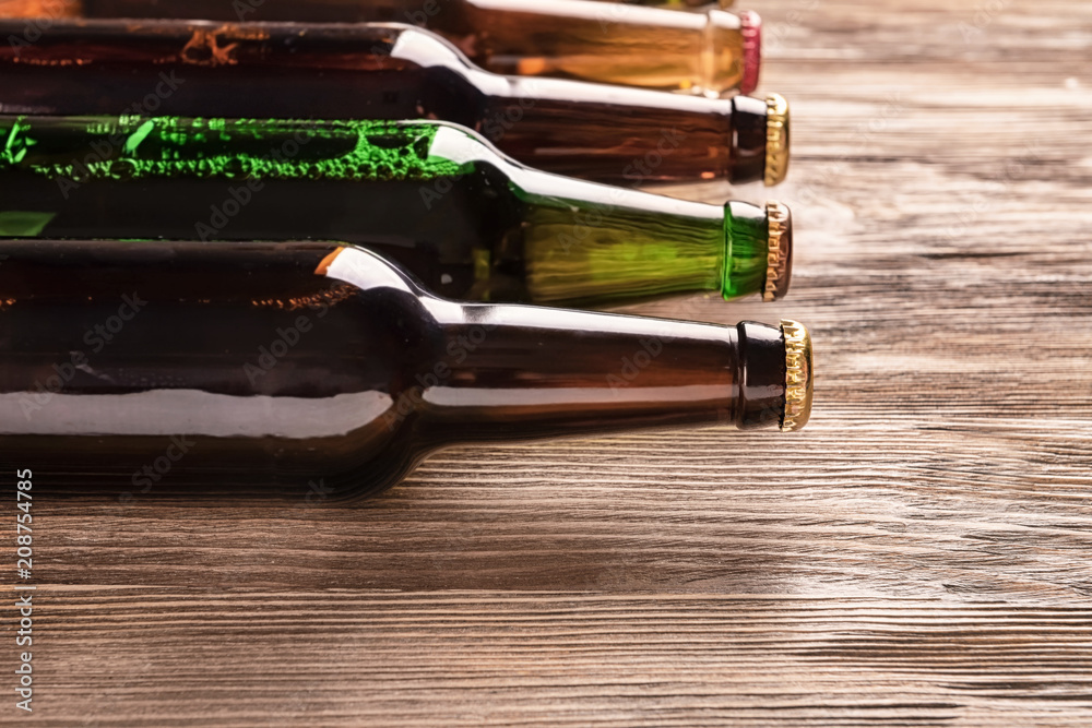 Glass bottles of beer on wooden background