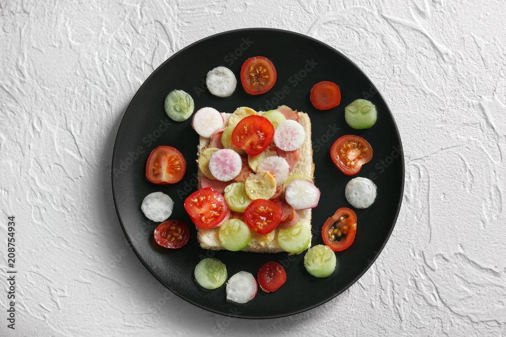 Plate with creative toast with vegetables for children on textured background