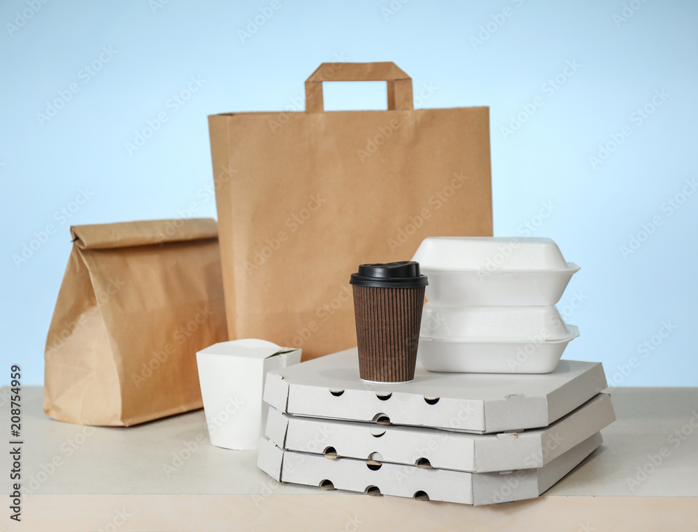 Different packages on table against color background. Food delivery service