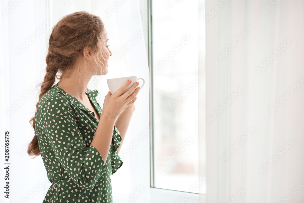 年轻女子在室内靠窗喝茶