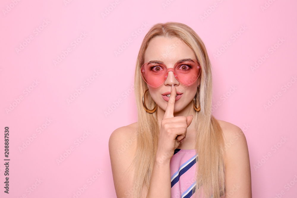 Beautiful young woman showing silence gesture on color background