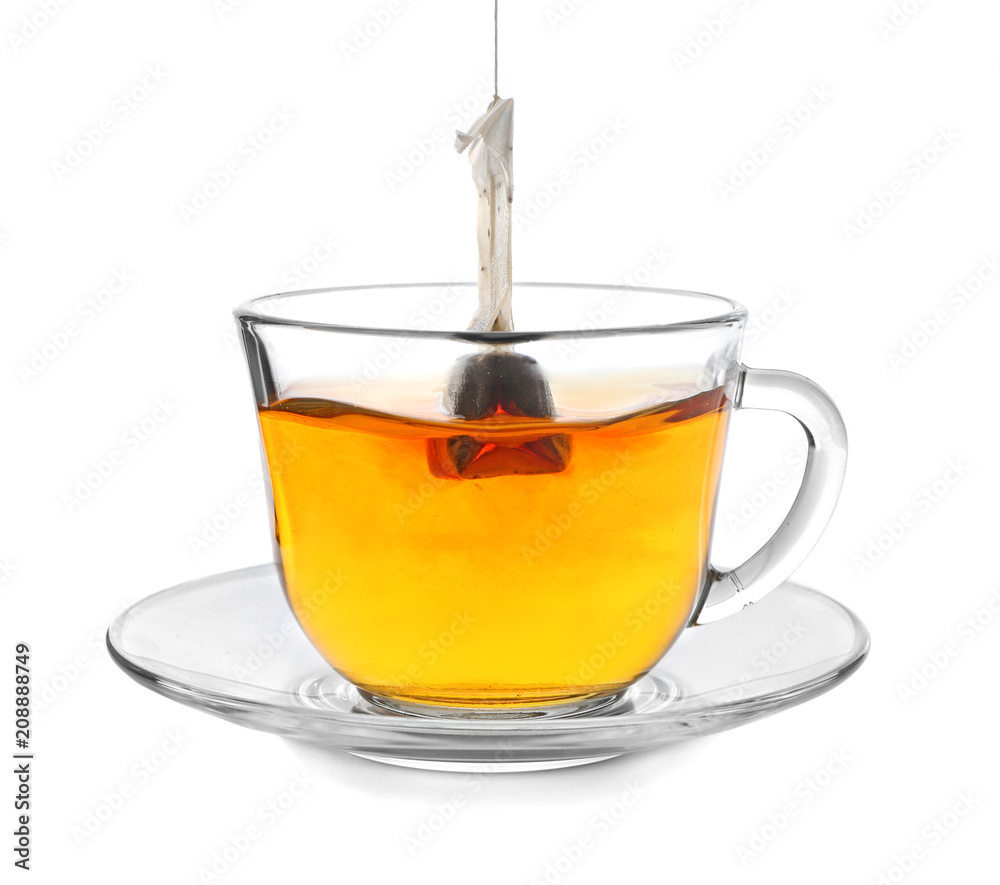 Brewing of hot beverage with tea bag in glass cup on white background