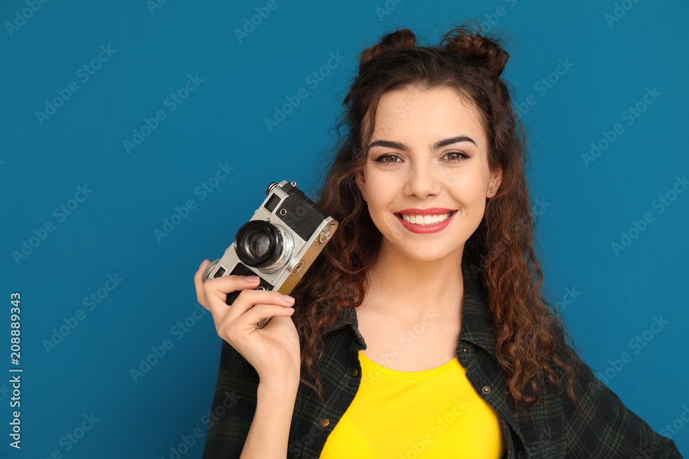 Portrait of beautiful young woman with camera on color background