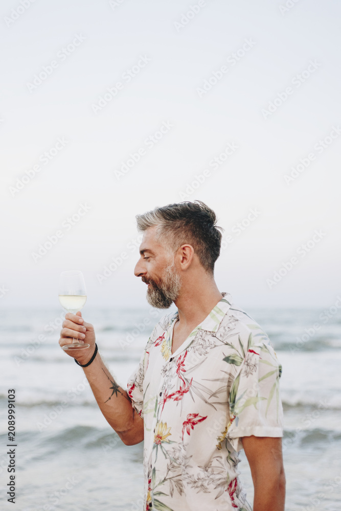 Man drinking a glass of wine by the beach