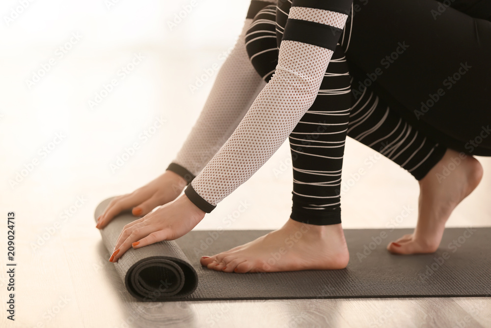 Beautiful woman with yoga mat indoors