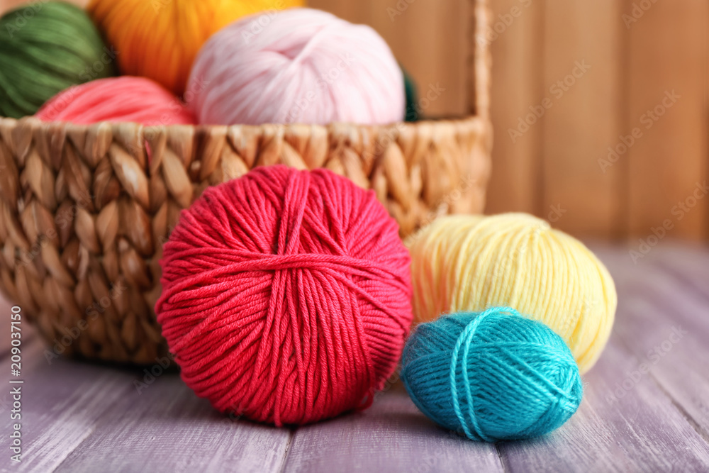 Wicker basket with knitting yarn on wooden table