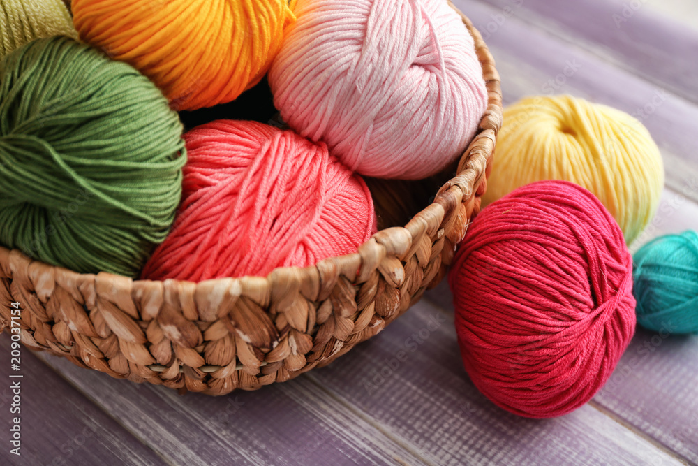 Wicker basket with knitting yarn on wooden table